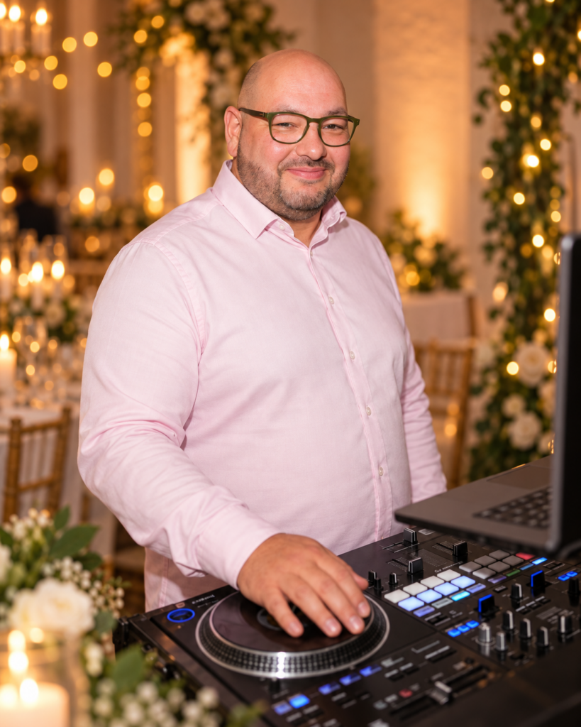 DJ Lito am DJ-Pult in warmer Hochzeitskulisse