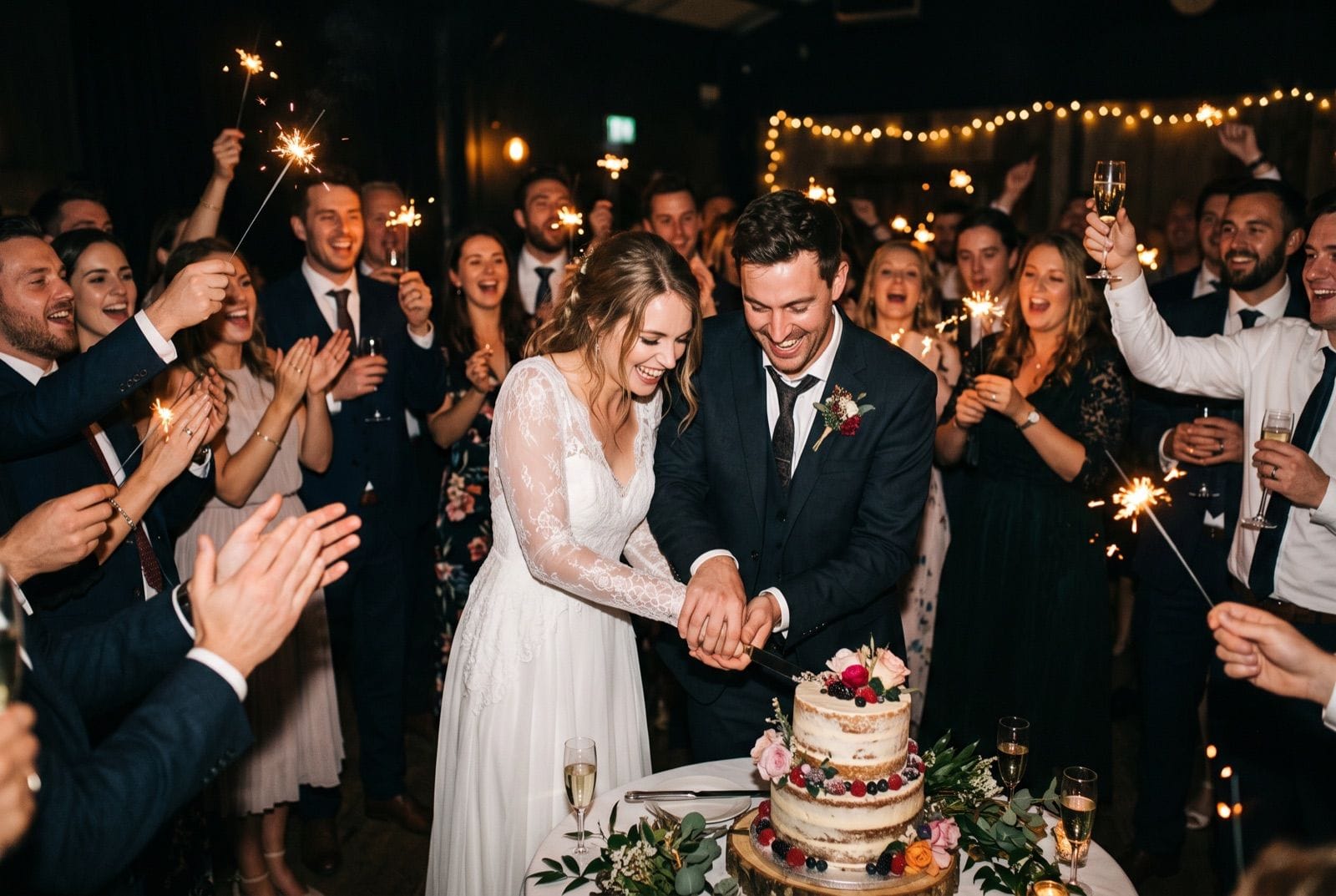 Brautpaar schneidet um Mitternacht die Hochzeitstorte an, Gäste mit Wunderkerzen